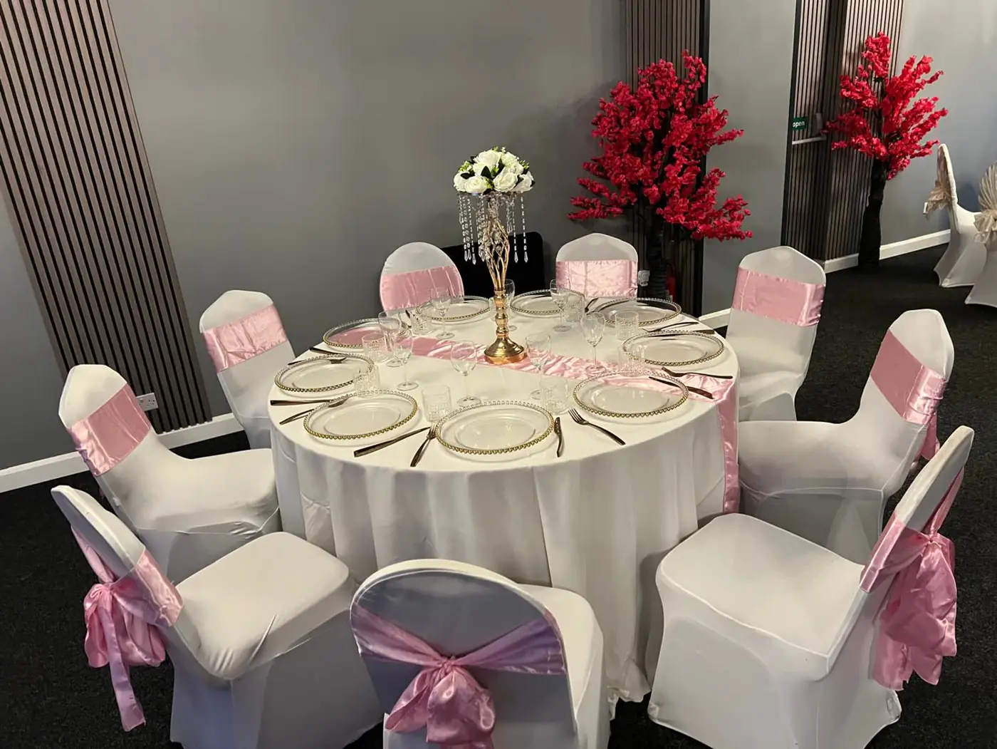 Banquet table with blush pink chair sashes and runner, beaded charger plates and a crystal centrepiece