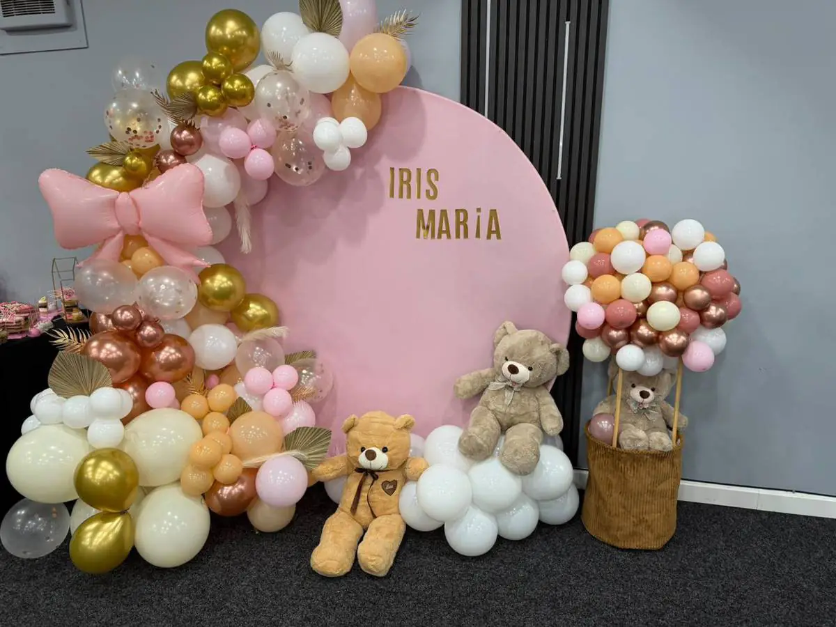Pink, cream and gold balloon display with a large pink bow, teddy bears and a personalised round backdrop