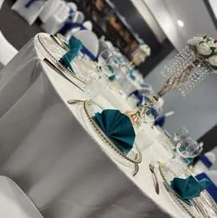 Close-up of a place setting with a teal folded napkin, charger plate and crystal glassware