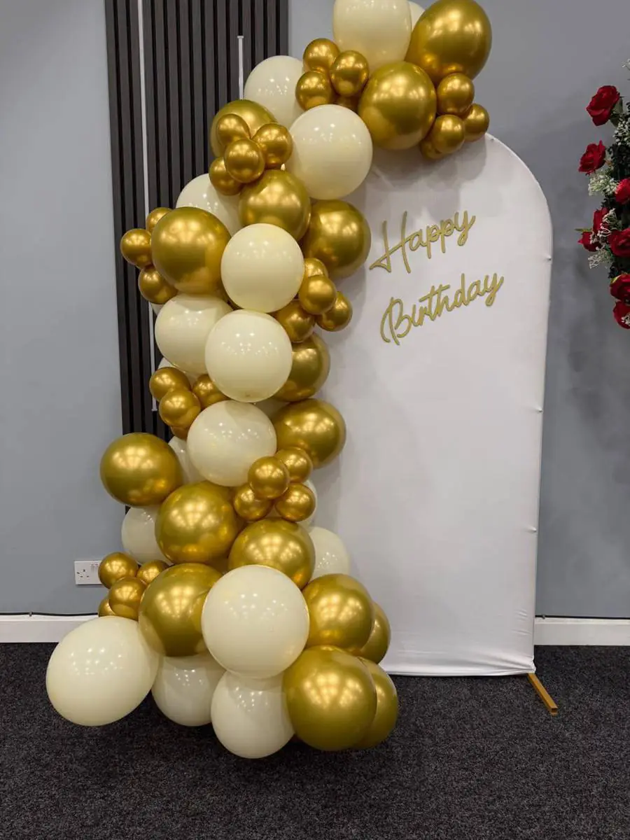 Gold and cream balloon garland around a 'Happy Birthday' backdrop