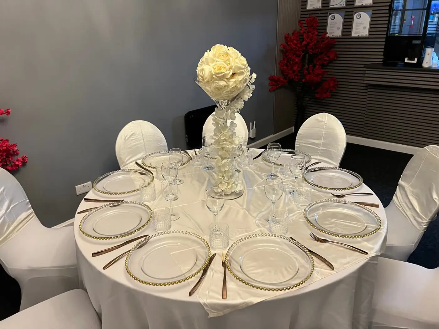 Classic white banquet table with crystal glassware, beaded charger plates and a white floral centrepiece